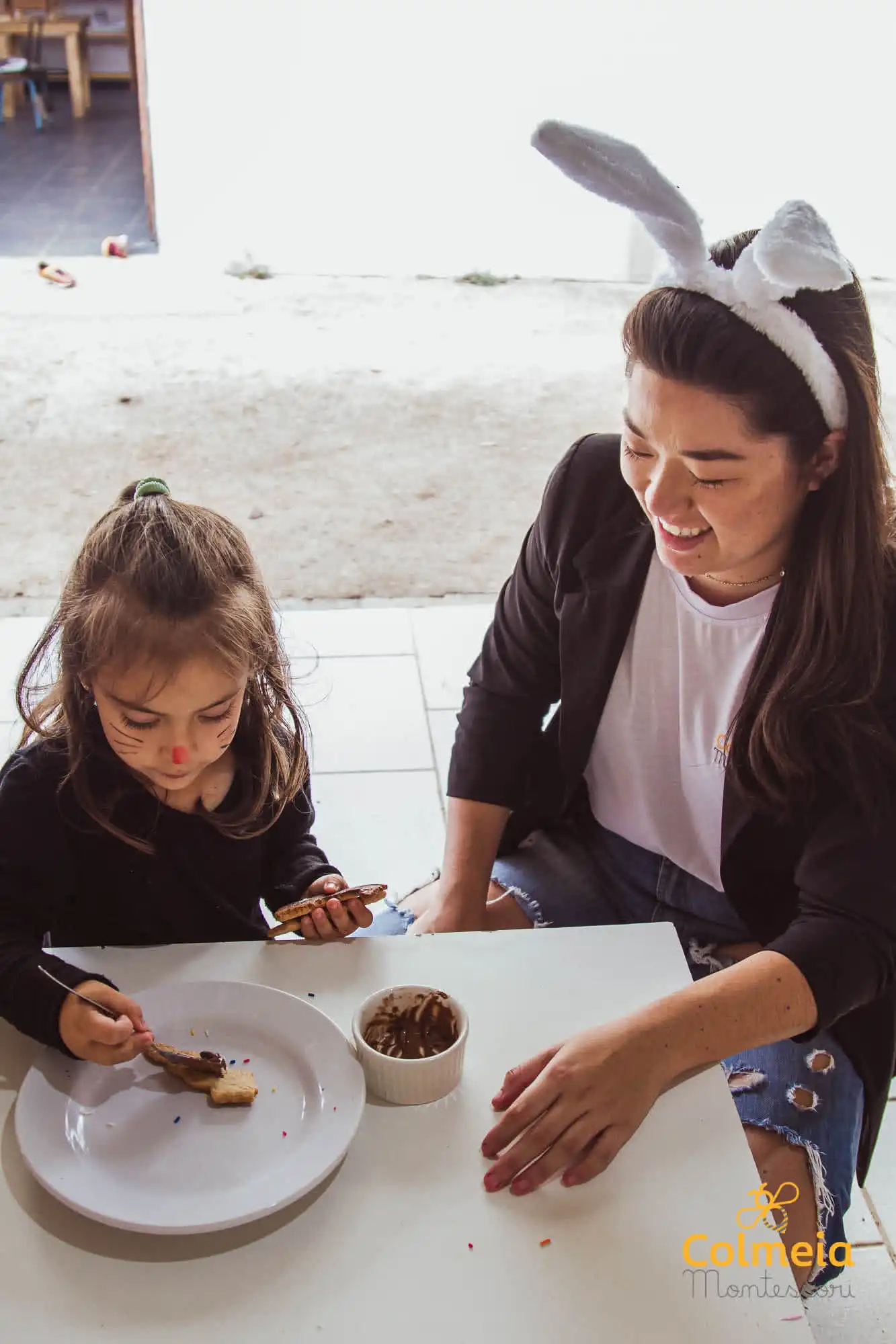 criança confeitando um biscoito com supervisão de um adulto